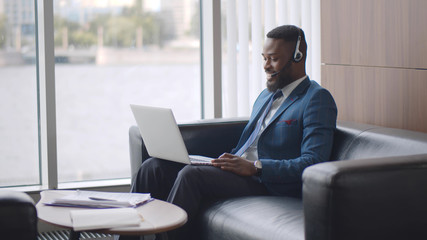 Young african businessman in headset having video conference with client on laptop