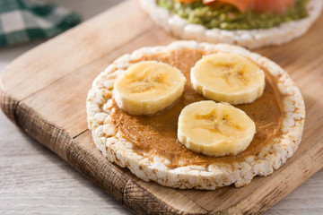 Puffed rice cake with banana and peanut butter on wooden table.	