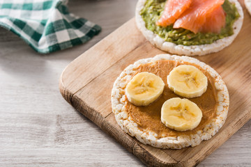 Puffed rice cake with banana and peanut butter on wooden table.	