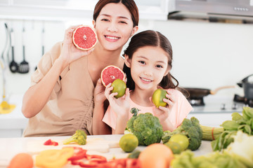 happy Mother and child daughter  preparing the vegetables and fruit in kitchen