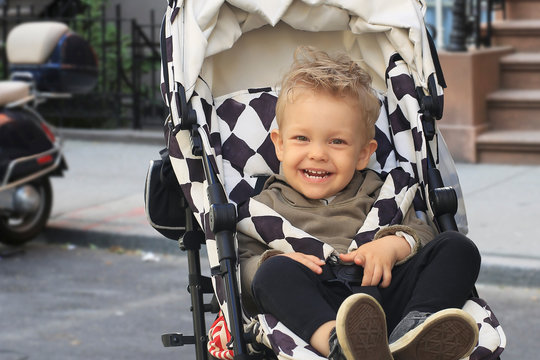 Little beautiful boy in a stroller on the street