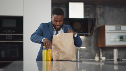 Young african businessman coming back home with groceries bags
