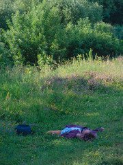 A person lying in the grass in the woods in summer