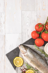 Fresh raw trout with olive oil, tomato, pepper, salt and lemon. Healthy Mediterranean food, top view, flat lay. Free space for text.