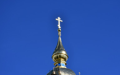 Fototapeta na wymiar The dome of the Orthodox Church with a Golden cross against the blue sky.