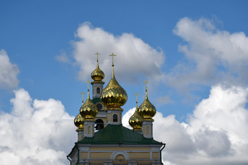 Fototapeta na wymiar Golden domes with a cross on the background of blue sky and clouds.