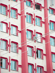 A white and red building with the sky reflecting in the widows behind wires