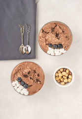Chocolate mousse dessert placed on white background with hazelnuts, dark chocolate, blueberries, top view, flat lay. Served and ready to eat.