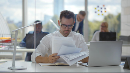 Fototapeta na wymiar Young happy businessman working in office reading documents at workplace