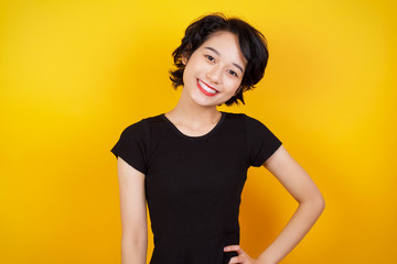 Studio shot of cheerful businesswoman keeps hand on hip, smiles broadly, anticipates for surprise prepared by friends on her birthday, isolated over  background.