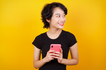 Image of a happy young beautiful woman posing isolated over bright background listening to music with earphones using mobile phone.