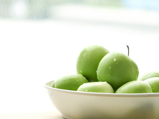 Ripe green apple raw fruit in white bowl on wooden table, healthy organic fresh produce