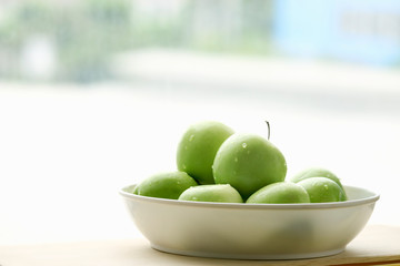 Ripe green apple raw fruit in white bowl on wooden table, healthy organic fresh produce