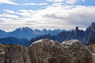 Dolomites Alps, view from Three Merlons (Drei Zinnen), South Tirol, Italy, UNESCO world heritage site, colorful rock layers, blue sky with clouds background, a sunny day in autumn