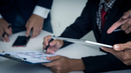 The hand pointing at the laptop and the businessman reading a graph in the background