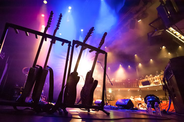 rack of electric guitars under stage lighting in a theatre - 371436754