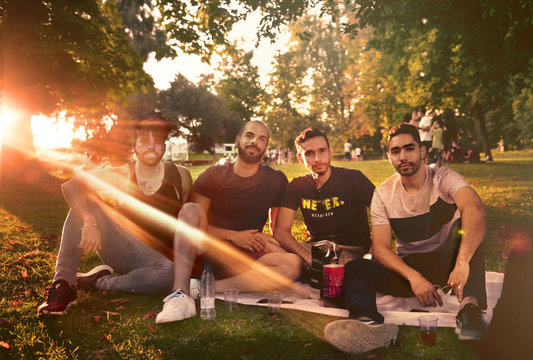 grupo de j&oacute;venes estudiantes en el parque alegres conversando posando de botell&oacute;n al aire libre fiesta en El Retiro con rayo de Sol