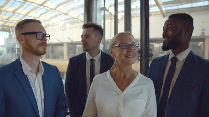 Diverse business colleagues smiling and loking away riding in elevator.