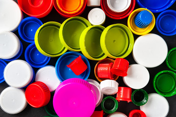 Top view of many plastic bottle caps. Caps for bottles from recycled plastic. Separate garbage collection. Recycling of plastic for prosthetics. Selective focus.