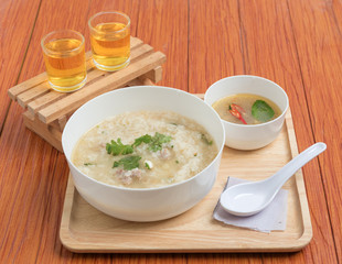 Porridge is placed on a wooden tray and there are two tea glasses. Breakfast