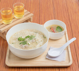 Porridge is placed on a wooden tray and there are two tea glasses. Breakfast