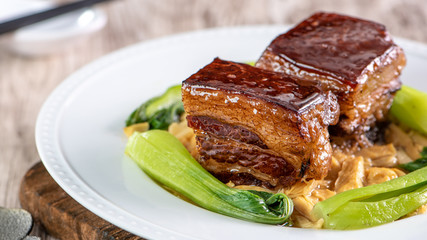 Dong Po Rou (Dongpo pork meat) in a beautiful blue plate with green broccoli vegetable, traditional festive food for Chinese new year cuisine meal, close up.