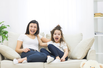 Photo of mother and daughter sitting playing on sofa.