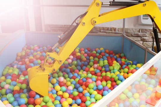 Yellow escavator and colorful plastic balls on children's playground