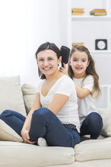 Photo of smiling mother and daughter on the sofa.