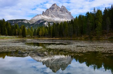 Fototapeta na wymiar Tre Cime (Three Peaks) di Lavaredo Natural Park, Dolomites mountains, South Tirol, Italy, a lake in front, reflections on water surface, autumn landscape, blue sky with clouds background, a sunny day