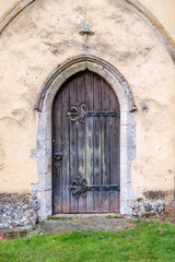 Fototapeta na wymiar Old wooden door surrounded by an ornate stone facade in a Norfolk church