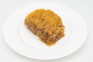 Kataifi a Traditional Greek Pastry with Shredded Filo Dough on a White Plate with a White Background