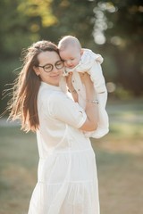 Young beautiful family walks in the park. Family portrait in the sunset light. Summer picnic.