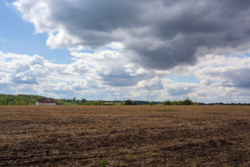 Crop field with a lonely house and dark clouds