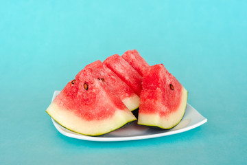 Water melon slices on a plate on blue background