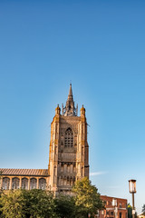 Fototapeta premium Impressive Anglican church spire against a bright blue sky on a sunny summer's day.