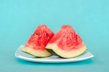 Water melon slices on a plate on blue background