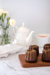 French dessert Canele with white teapot and cup of tea.