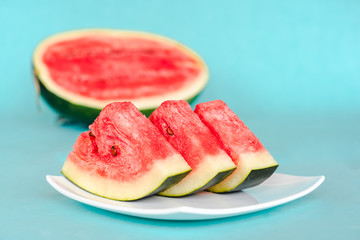 Water melon slices on a plate on blue background