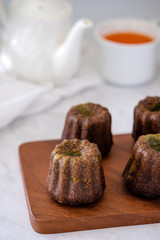 French dessert Canele with white teapot and cup of tea.