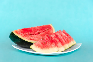 Water melon slices on a plate on blue background