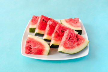 Water melon slices on a plate on blue background