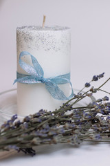 white candle with a bouquet of dried flowers