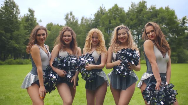 Girls cheerleaders with pompons blowing kisses smiling at camera