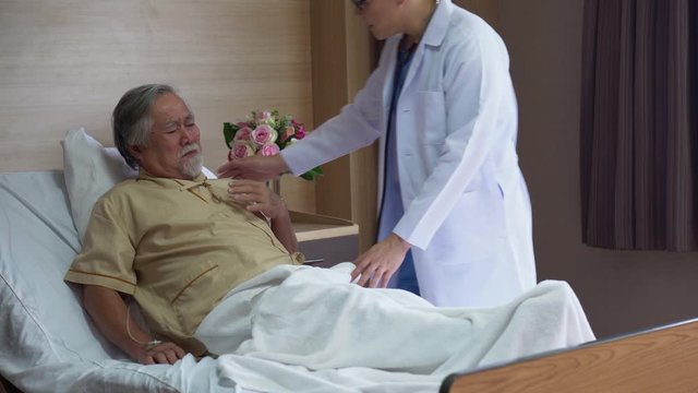 asian senior old man patient suffering from coughing while lying on bed and young doctor rushed in to check for the illness with stethoscope Listening heart and lungs in hospital.