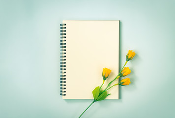 Spiral Notebook or Spring Notebook in Unlined Type and 4 Orange Flowers at Bottom Right on Blue Pastel Minimalist Background. Spiral Notebook Mockup on Center Frame in Vintage Tone