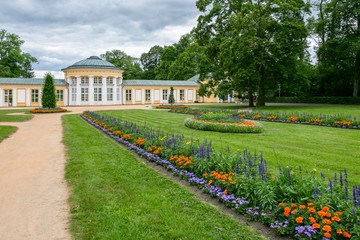 Marianske Lazne / Czech Republic - July 12 2020: View of the Ferdinand pavilion standing in a park with trees, green lawn and colorful flowers on a summer day. 