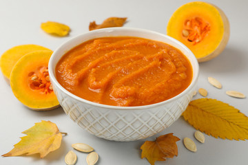 Composition with bowl of pumpkin puree on gray background, close up