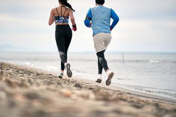 Male and female running on the beach; Healthy lifestyle concept