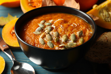 Composition with pumpkin soup with seeds on wooden background, close up